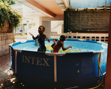Every summer our neighbours take out a small swimming pool in the yard behind our flat. We can hear her children and their friends play there during the hot days. Occasionally they are forced to empty and refill it because drunks have come to bathe there during the night, leaving floating beer bottles and cigarettes behind. - © Maciek Pożoga