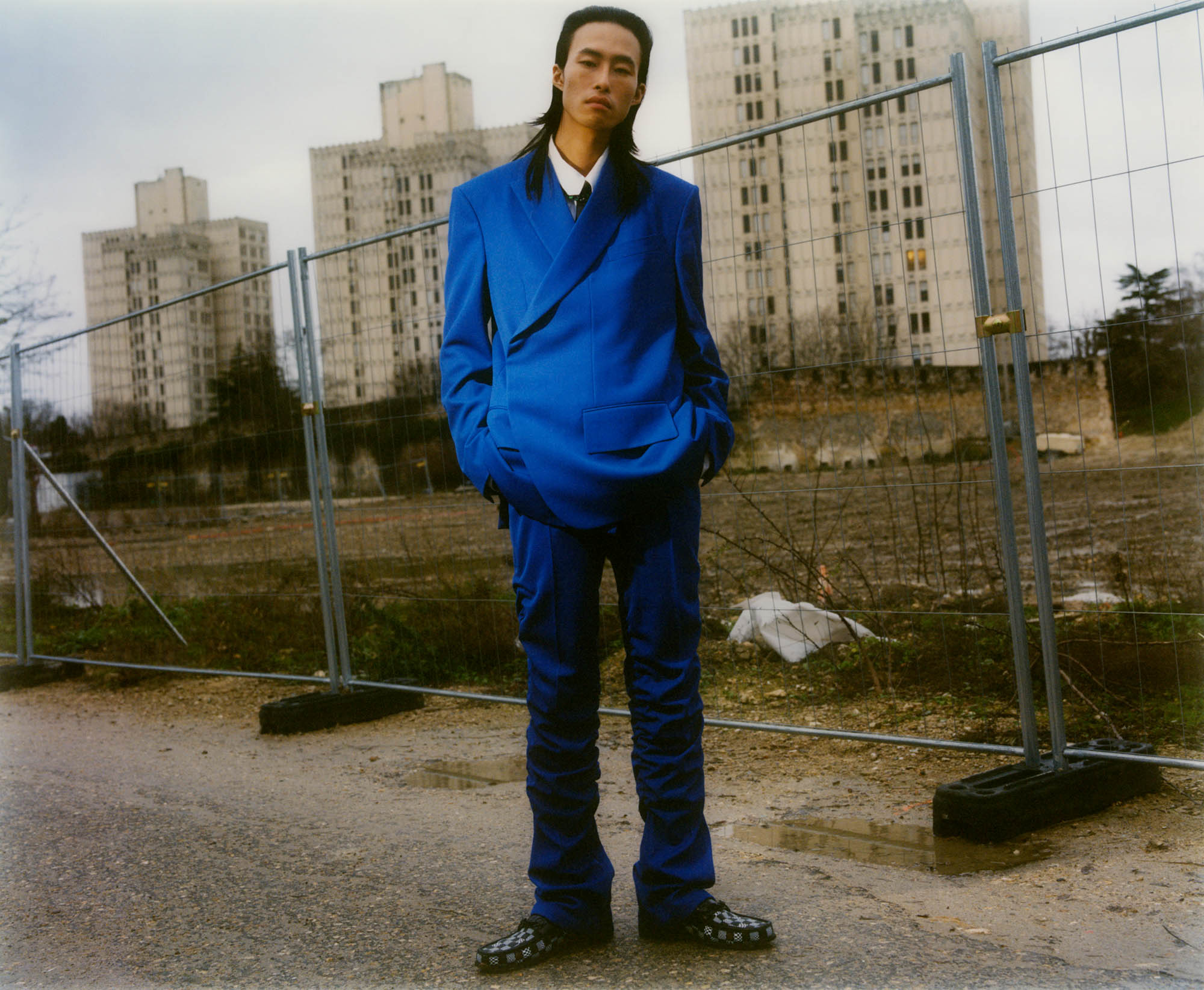 Fashion editorial for *SSAW* Magazine shot at my studio and around. As im getting a bit bored of straightforward documentary photography (especially in those times), I was happy to work on portraying fictional local characters I could have bumped into in those familiar surroundings. Here Ji Seok at a *Grand Paris* construction site in Fort d'Aubervilliers. *{Styling by Tuomas Laitinen. Hair by Yuji Okuda, Make-up by Satoko Watanabe. Casting by Rene de Bathory. Models : Xu SuMin Kim and Ji Seok. Photo assistants : William Fleming and Alassan Diawara}* - © Maciek Pożoga